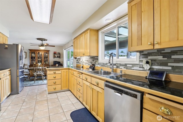 kitchen with stainless steel appliances, a sink, backsplash, and light brown cabinets