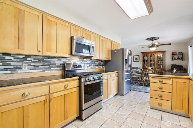 kitchen featuring appliances with stainless steel finishes, backsplash, light tile patterned floors, a ceiling fan, and tile counters