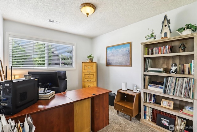 carpeted home office featuring a textured ceiling