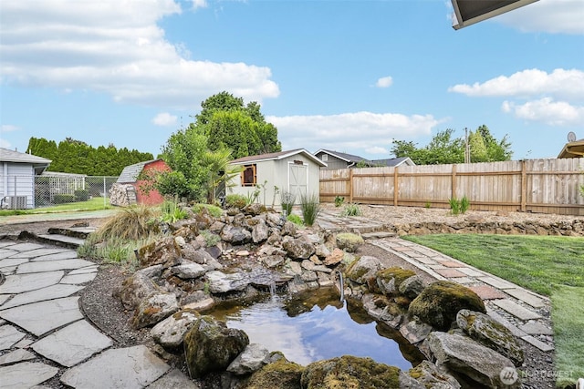 fenced backyard with a garden pond, a shed, and an outdoor structure