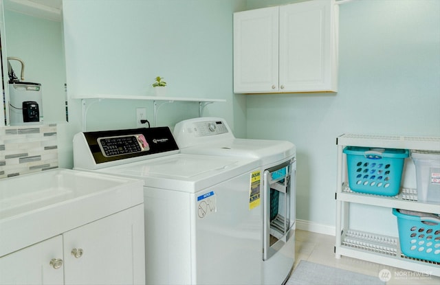 515 N Shelley Ave, Othello, WA 99344 - laundry area with separate washer and dryer, cabinet space, water heater, light tile patterned flooring, and baseboards