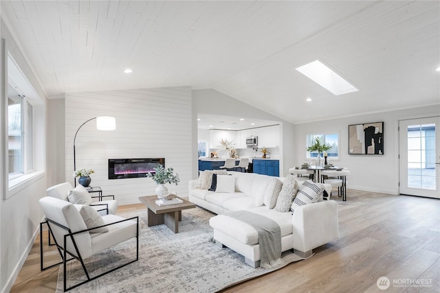 22406 121st Dr NE, Arlington, WA 98223 - living room with vaulted ceiling, light wood finished floors, a skylight, baseboards, and a large fireplace