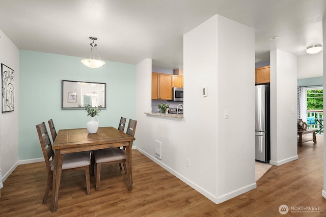 dining space with light wood-style flooring and baseboards