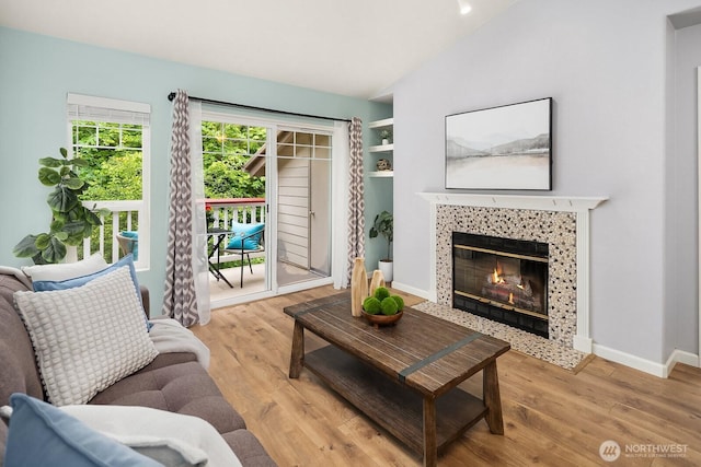 living room with lofted ceiling, a fireplace, wood finished floors, and baseboards