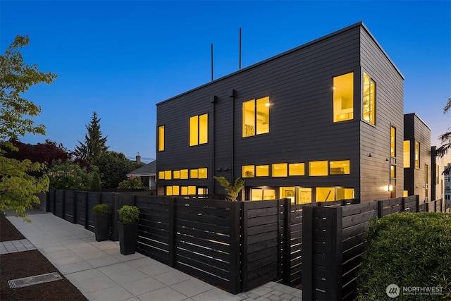 back of property at dusk with a fenced front yard and a gate