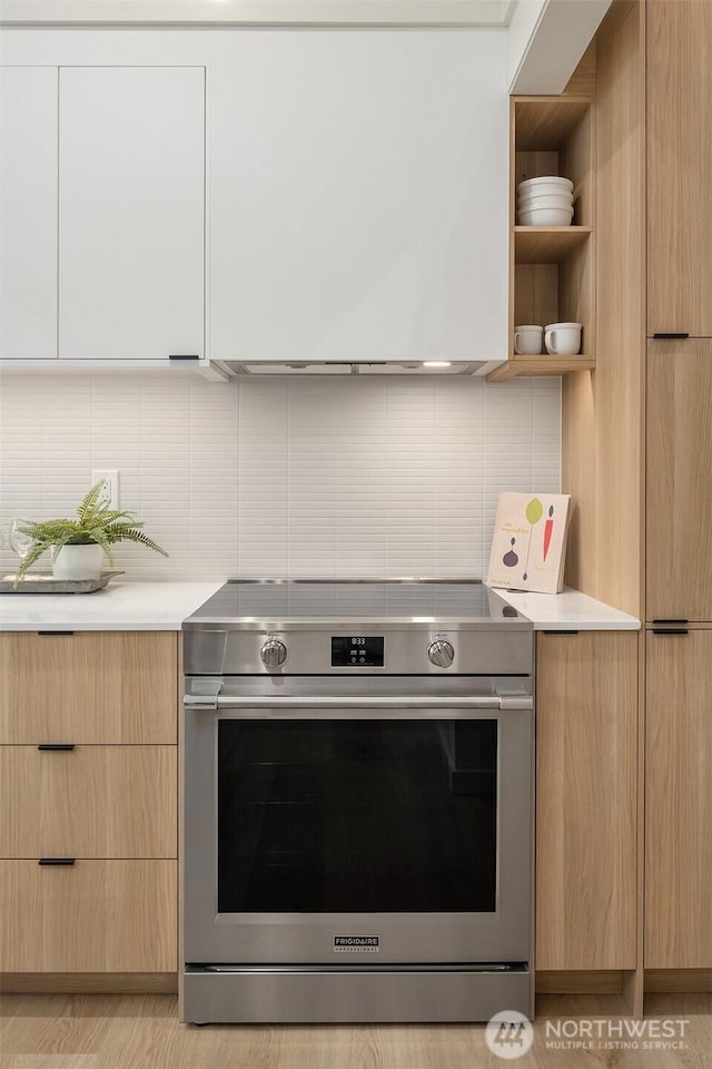 kitchen with stainless steel electric stove, modern cabinets, and light brown cabinets