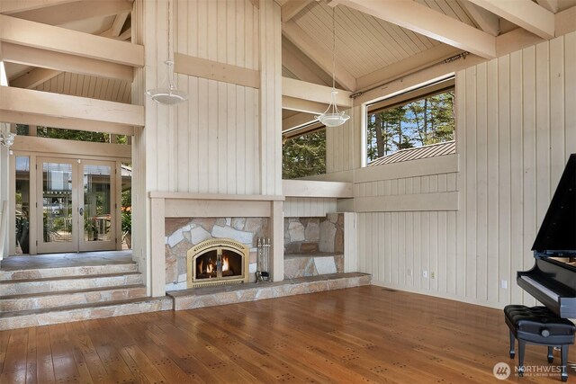 871 Deer Point Rd, Orcas Island, WA 98279 - unfurnished living room featuring beamed ceiling, hardwood / wood-style floors, wood walls, an outdoor stone fireplace, and high vaulted ceiling