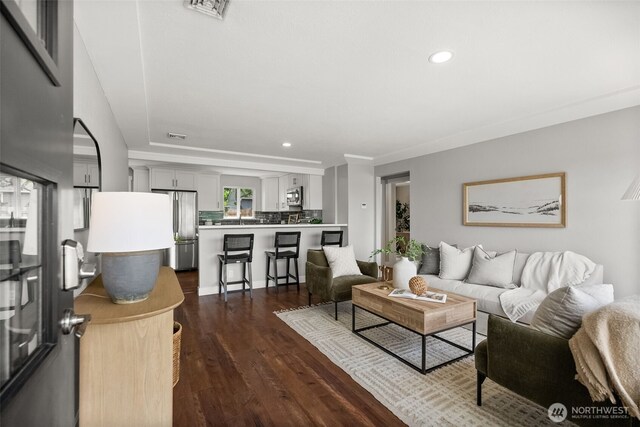 living room with recessed lighting, dark wood finished floors, and ornamental molding