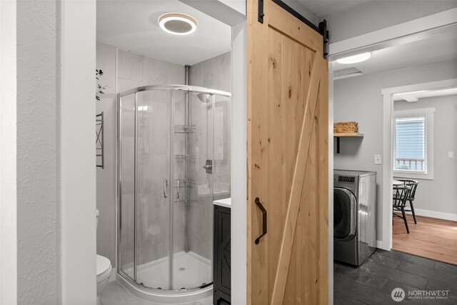 bathroom featuring washer / clothes dryer, a shower stall, toilet, and vanity