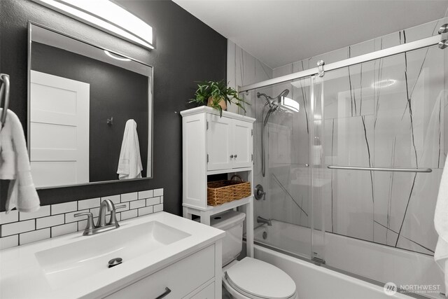 bathroom featuring decorative backsplash, vanity, enclosed tub / shower combo, and toilet