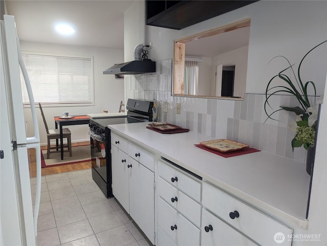 kitchen with black / electric stove, white cabinets, tasteful backsplash, light countertops, and light tile patterned floors