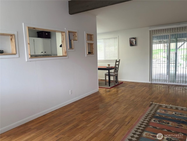 hall featuring plenty of natural light, wood finished floors, baseboards, and beamed ceiling