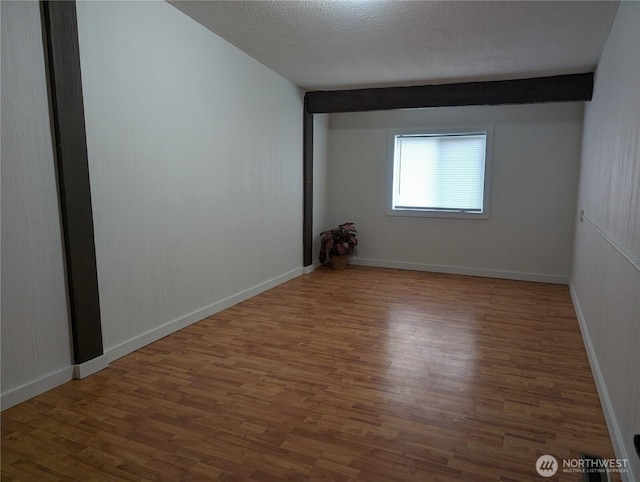 spare room featuring wood finished floors, a textured ceiling, and baseboards