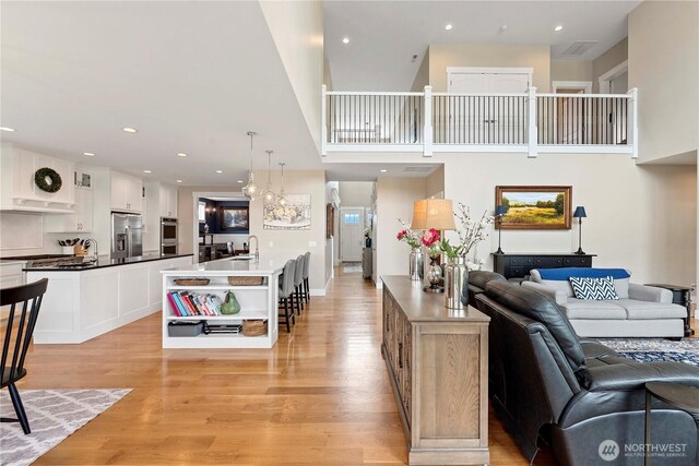 living area featuring light wood-type flooring, recessed lighting, and a high ceiling