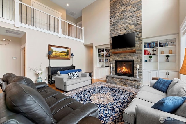 living room featuring a towering ceiling, wood finished floors, a fireplace, and built in features