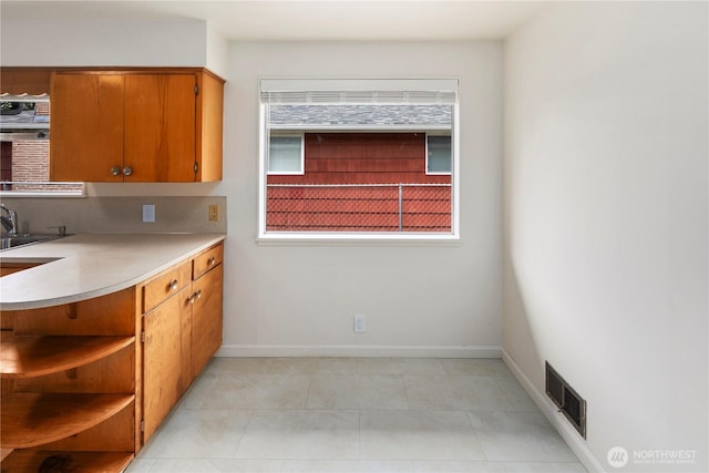 1113 S 72nd St, Tacoma, WA 98408 - kitchen featuring light countertops, baseboards, open shelves, and brown cabinetry