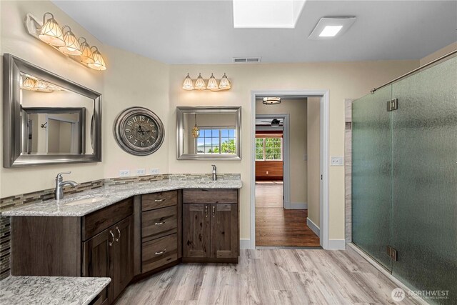 2060 5th St, Wenatchee, WA 98801 - bathroom featuring wood finished floors, double vanity, a shower stall, and baseboards