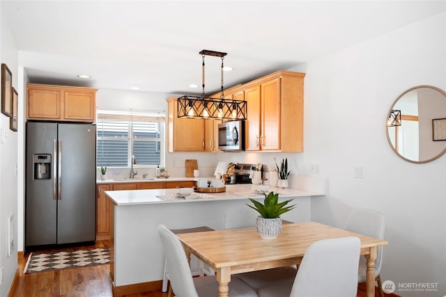 1123 N 94th St Unit A, Seattle, WA 98103 - kitchen featuring appliances with stainless steel finishes, a sink, light countertops, a peninsula, and wood finished floors