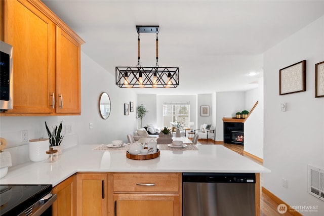 1123 N 94th St Unit A, Seattle, WA 98103 - kitchen with stainless steel dishwasher, open floor plan, a peninsula, light countertops, and wood finished floors