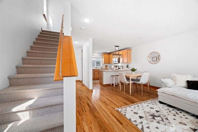 1123 N 94th St Unit A, Seattle, WA 98103 - stairway featuring wood finished floors, baseboards, recessed lighting, and a chandelier