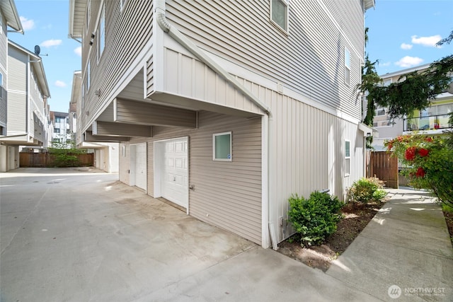 1123 N 94th St Unit A, Seattle, WA 98103 - view of side of property featuring a garage, concrete driveway, fence, and board and batten siding