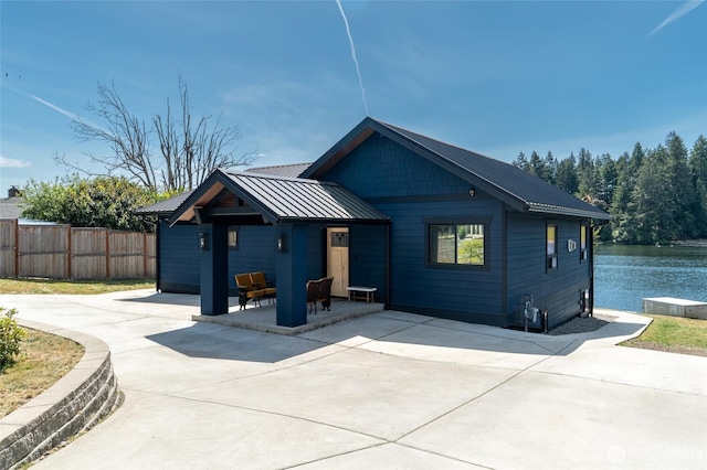 view of front facade with a patio area, fence, metal roof, and concrete driveway