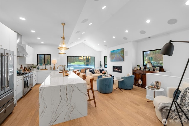 kitchen featuring high quality appliances, modern cabinets, wall chimney exhaust hood, white cabinets, and lofted ceiling