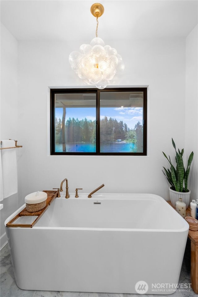 bathroom featuring a chandelier and a freestanding tub