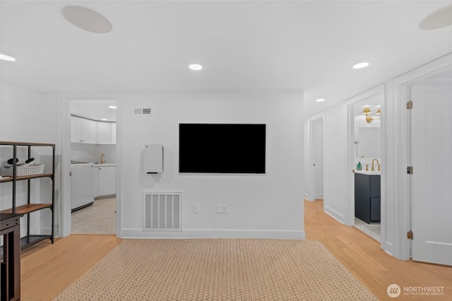 unfurnished living room featuring light wood-style flooring, recessed lighting, baseboards, and a sink