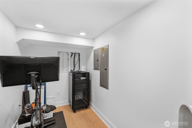 workout area with light wood-style floors, electric panel, recessed lighting, and baseboards
