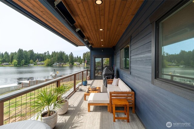 balcony with a water view, outdoor lounge area, and grilling area