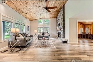 living room with wood finished floors, ceiling fan, vaulted ceiling, and a fireplace