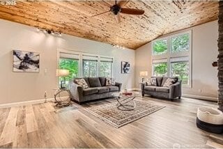 living room featuring wood finished floors, a ceiling fan, plenty of natural light, and vaulted ceiling