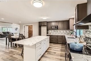 kitchen with stainless steel microwave, stove, healthy amount of natural light, and dark brown cabinetry