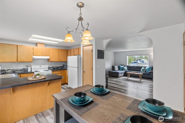 60 E Treewater Pl, Shelton, WA 98584 - kitchen featuring white appliances, arched walkways, under cabinet range hood, light wood-type flooring, and dark countertops