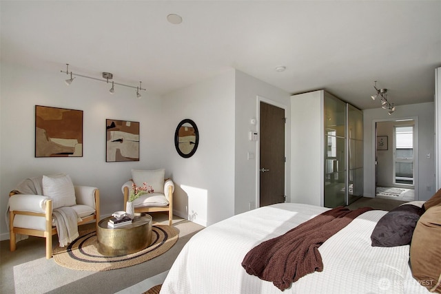 carpeted bedroom with rail lighting and baseboards