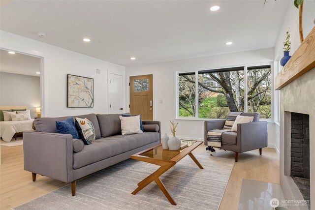 living area featuring light wood-type flooring, plenty of natural light, recessed lighting, baseboards, and a fireplace
