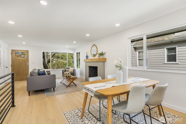 dining space with a fireplace, light wood-style flooring, recessed lighting, and baseboards