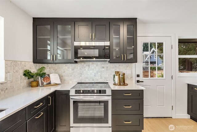kitchen with appliances with stainless steel finishes, light wood finished floors, light countertops, and decorative backsplash