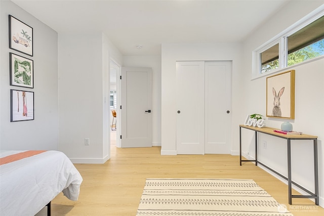 bedroom featuring light wood finished floors, baseboards, and a closet