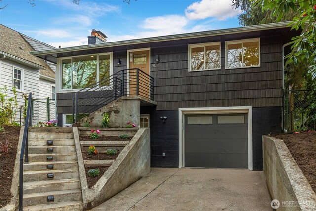 view of front facade featuring driveway, an attached garage, stairs, and a chimney