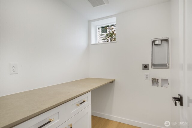 washroom with hookup for an electric dryer, baseboards, cabinet space, and light wood finished floors