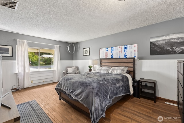 8511 31st St W, University Place, WA 98466 - bedroom featuring a wainscoted wall, hardwood / wood-style floors, and a textured ceiling