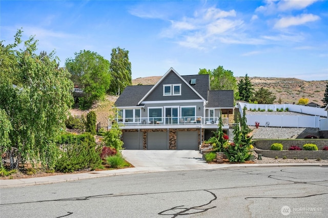 719 19th St NE, East Wenatchee, WA 98802 - view of front of house with a garage, stone siding, driveway, and fence