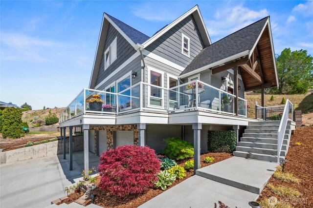 719 19th St NE, East Wenatchee, WA 98802 - view of side of home featuring stone siding, stairs, a garage, and a shingled roof