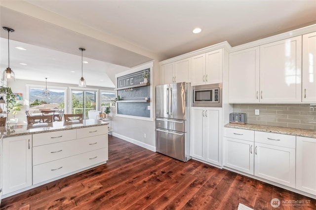 719 19th St NE, East Wenatchee, WA 98802 - kitchen with appliances with stainless steel finishes, dark wood-type flooring, white cabinetry, tasteful backsplash, and decorative light fixtures
