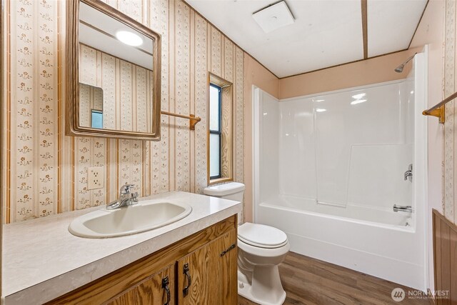 23920 50th Ave E, Graham, WA 98338 - full bath featuring wallpapered walls, toilet, wood finished floors, tub / shower combination, and vanity