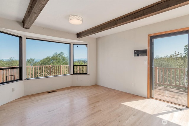 empty room with beamed ceiling and wood finished floors