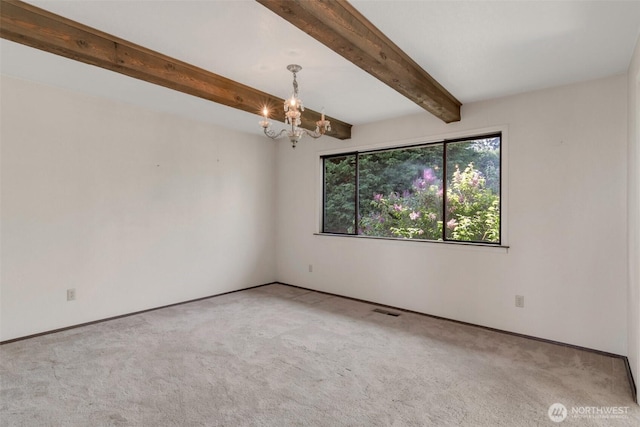 carpeted empty room featuring a chandelier, beam ceiling, and baseboards