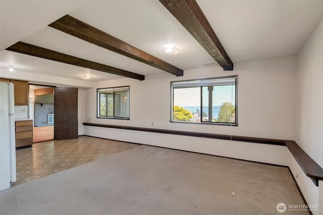 unfurnished living room with carpet floors, beam ceiling, baseboards, and a baseboard heating unit